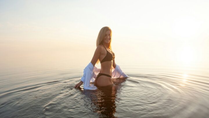 woman wearing black bikini set standing in the middle of body of water